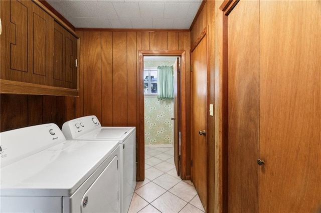 washroom featuring wood walls, cabinets, light tile patterned flooring, and washing machine and clothes dryer