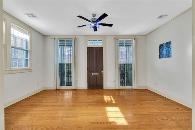 empty room with light wood-style flooring, crown molding, ceiling fan, and baseboards
