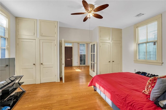 bedroom with light wood finished floors, multiple windows, a closet, and ceiling fan