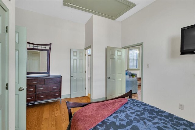 bedroom featuring hardwood / wood-style floors, a high ceiling, and ornamental molding