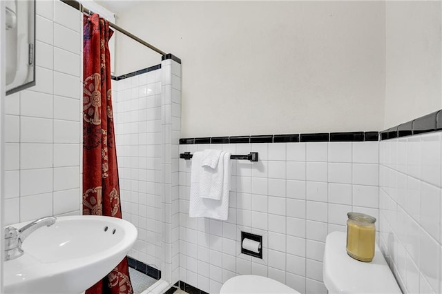 bathroom featuring a shower with curtain, toilet, sink, and tile walls