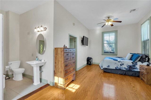 bedroom featuring light hardwood / wood-style flooring, ceiling fan, and sink