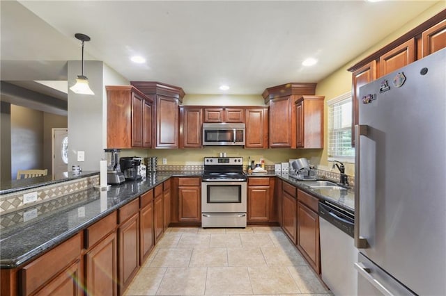 kitchen featuring sink, stainless steel appliances, dark stone countertops, pendant lighting, and light tile patterned floors