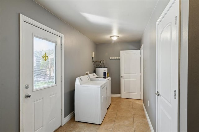 washroom featuring washer and dryer, light tile patterned flooring, and water heater