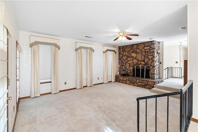 unfurnished living room featuring ceiling fan, a fireplace, and light carpet