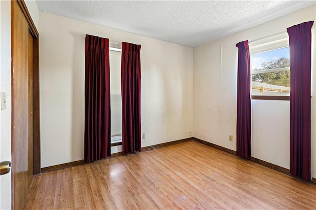 unfurnished room featuring a textured ceiling and light hardwood / wood-style floors