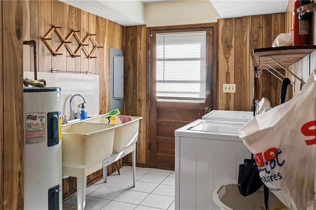 washroom featuring washing machine and clothes dryer, wooden walls, water heater, and light tile patterned flooring