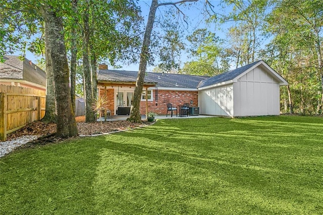 rear view of property featuring a yard, central AC, and a patio area