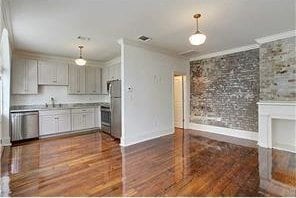 kitchen featuring stainless steel appliances, hanging light fixtures, crown molding, and dark hardwood / wood-style floors