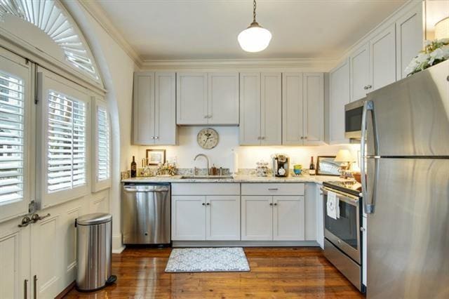 kitchen featuring white cabinets, sink, appliances with stainless steel finishes, decorative light fixtures, and dark hardwood / wood-style flooring