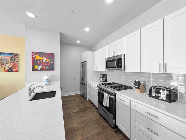 kitchen with appliances with stainless steel finishes, white cabinetry, dark wood-type flooring, and sink