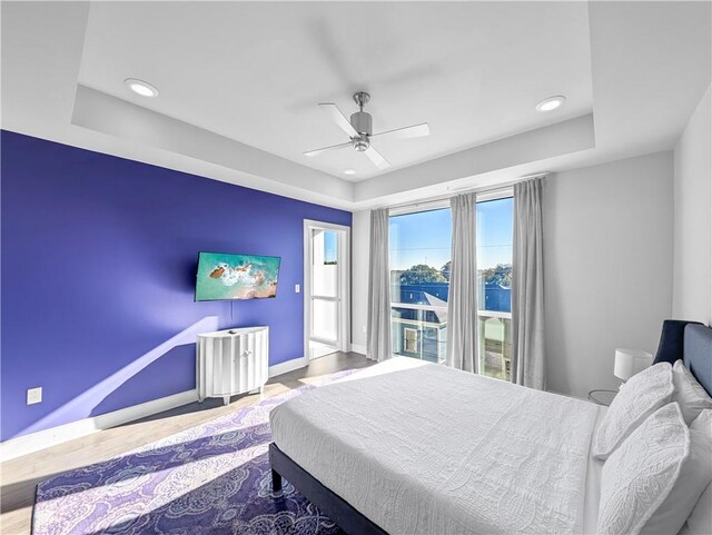 bedroom with a raised ceiling, ceiling fan, and hardwood / wood-style floors