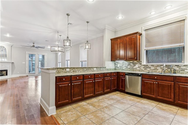 kitchen with kitchen peninsula, sink, stainless steel dishwasher, and decorative light fixtures