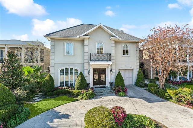 front facade featuring french doors, a balcony, and a garage