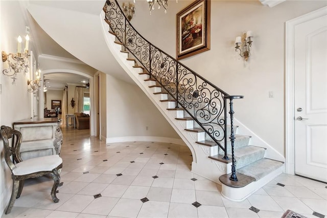 staircase with tile patterned floors, a chandelier, and ornamental molding