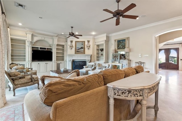 living room with ceiling fan, built in features, light tile patterned floors, and ornamental molding