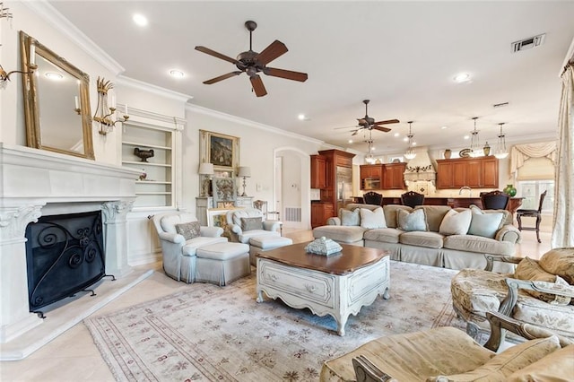 living room featuring built in shelves, ceiling fan, crown molding, and light tile patterned flooring