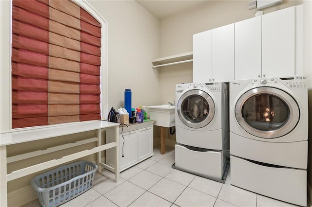 laundry area with cabinets, washing machine and dryer, light tile patterned floors, and sink