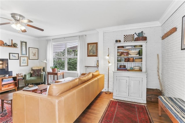 living room featuring ceiling fan, light hardwood / wood-style flooring, brick wall, and ornamental molding