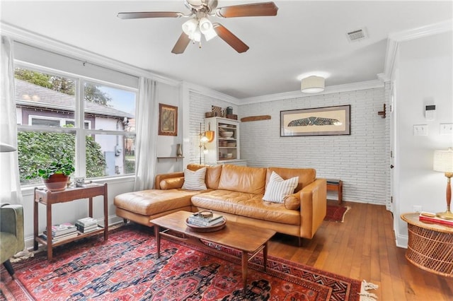 living room featuring hardwood / wood-style floors, ceiling fan, ornamental molding, and brick wall