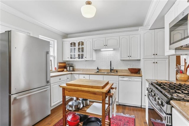 kitchen featuring ornamental molding, stainless steel appliances, sink, hardwood / wood-style flooring, and white cabinets