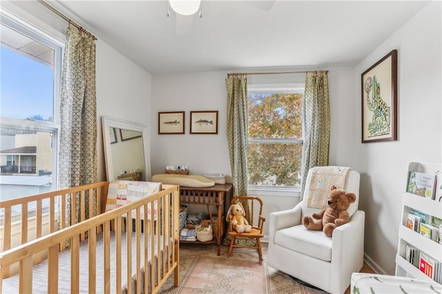 bedroom with ceiling fan and a nursery area