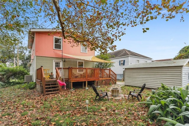 rear view of property featuring a wooden deck, a shed, and central AC