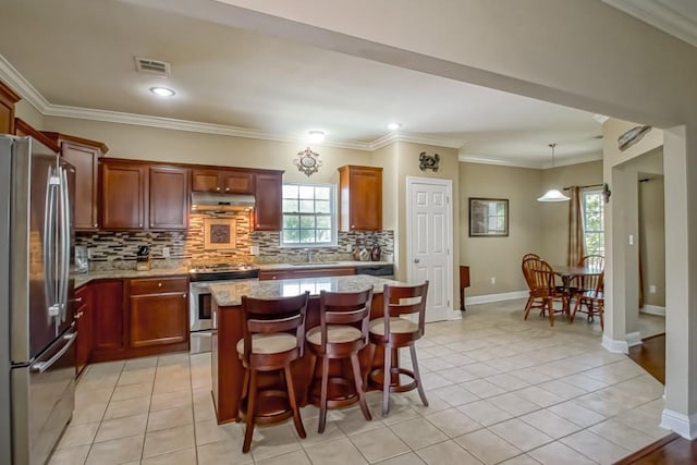 kitchen featuring pendant lighting, stainless steel appliances, a kitchen island, and light tile patterned flooring