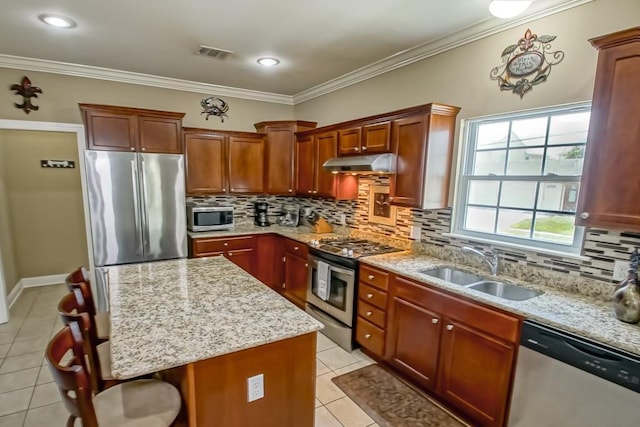 kitchen with appliances with stainless steel finishes, a center island, ornamental molding, and sink