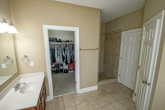 bathroom with tile patterned floors, vanity, and tiled shower