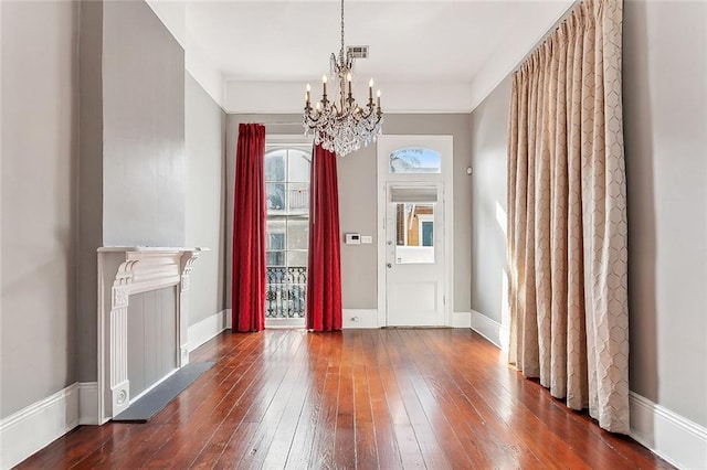 foyer featuring baseboards, dark wood-type flooring, a notable chandelier, and visible vents