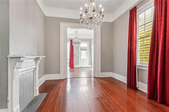 interior space featuring baseboards, wood-type flooring, a chandelier, and crown molding