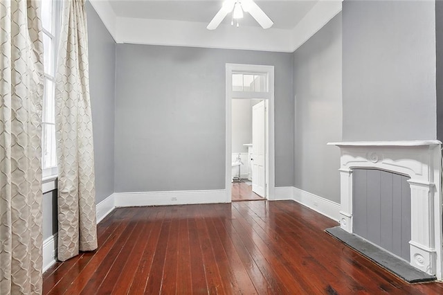 unfurnished living room featuring hardwood / wood-style flooring, baseboards, and ceiling fan