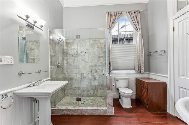 full bathroom with a wainscoted wall, toilet, wood finished floors, and a stall shower