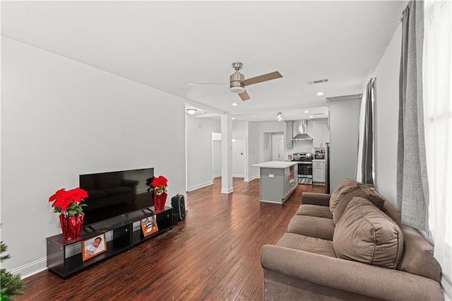 living room featuring ornate columns, ceiling fan, and dark hardwood / wood-style floors