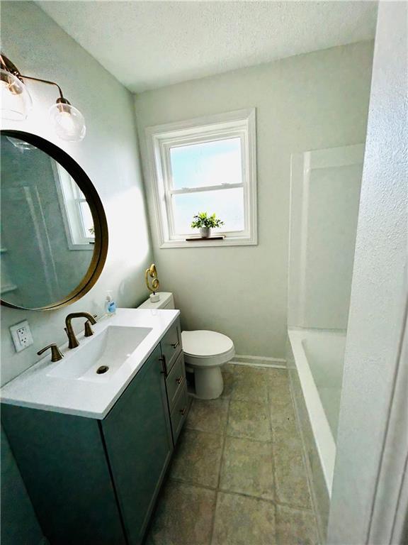 full bathroom featuring shower / washtub combination, vanity, a textured ceiling, and toilet