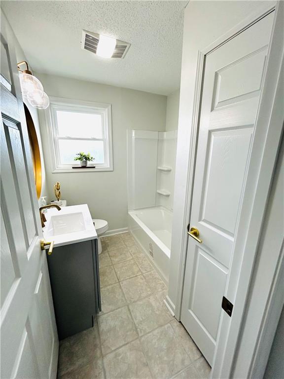 full bathroom featuring a textured ceiling, vanity, toilet, and shower / bathtub combination