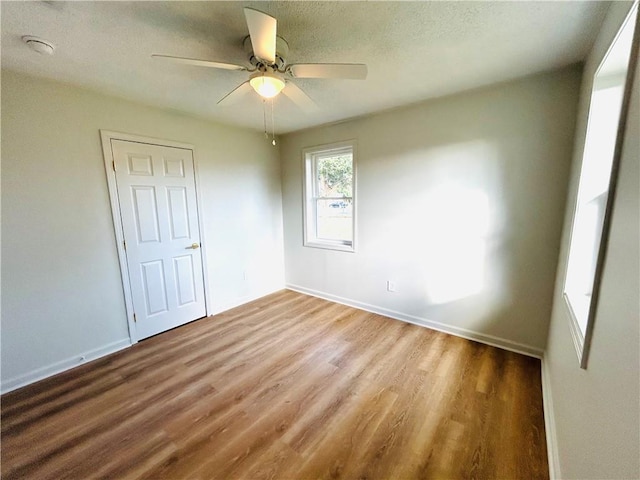 unfurnished bedroom with ceiling fan, a textured ceiling, and hardwood / wood-style flooring