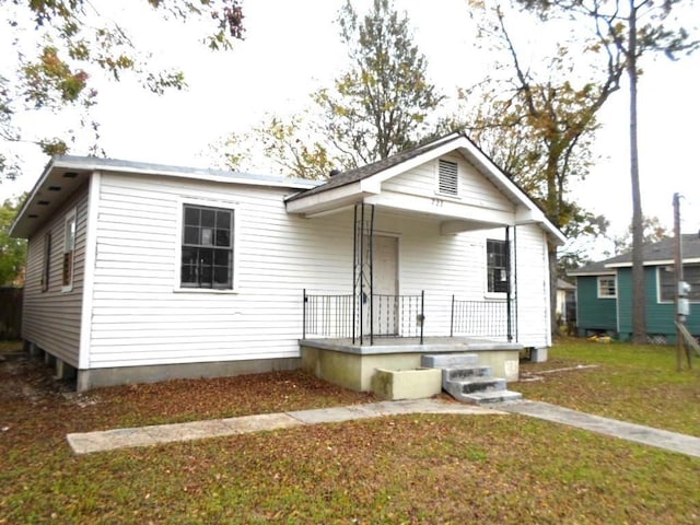 bungalow with covered porch and a front lawn