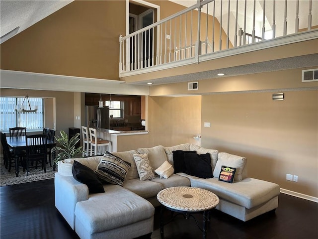 living room with a wealth of natural light, high vaulted ceiling, and dark hardwood / wood-style floors