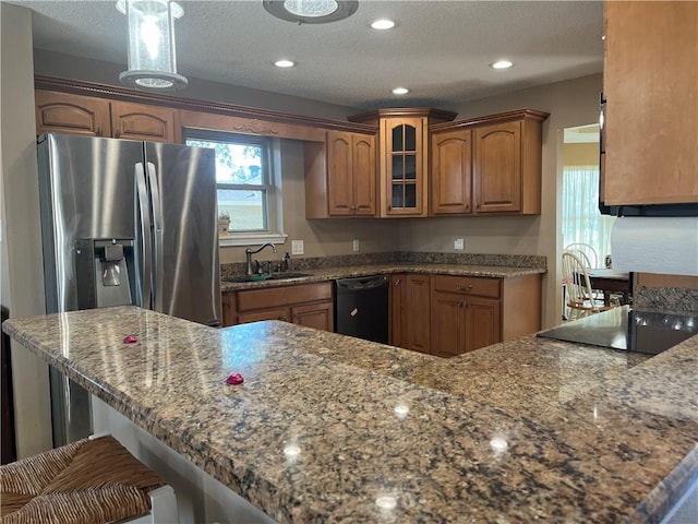 kitchen with kitchen peninsula, stainless steel refrigerator with ice dispenser, dark stone counters, sink, and dishwasher