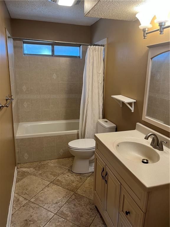 full bathroom featuring vanity, toilet, a textured ceiling, and shower / tub combo