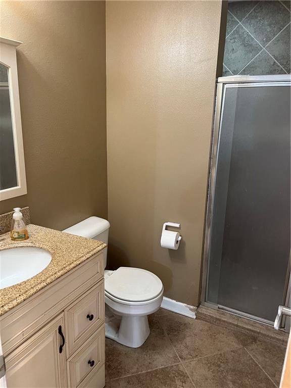 bathroom with vanity, a shower with shower door, and toilet