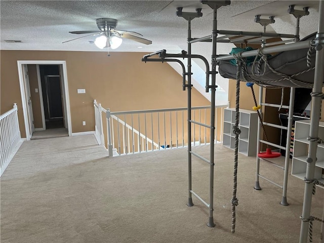 basement featuring carpet, a textured ceiling, and ceiling fan