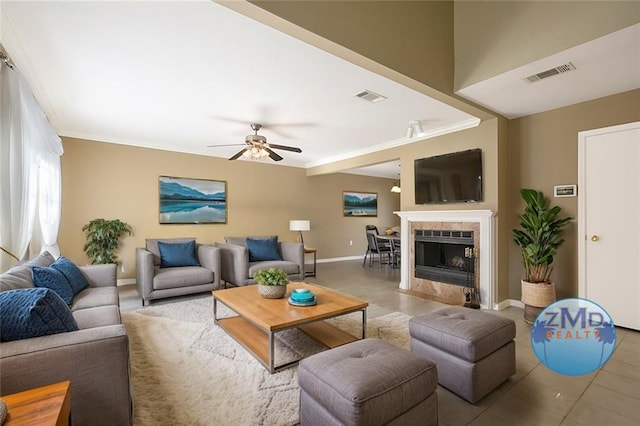 tiled living room featuring a tile fireplace, ceiling fan, and ornamental molding