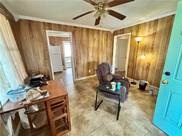 sitting room with crown molding, ceiling fan, and wood walls