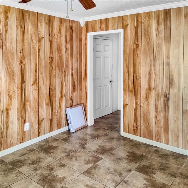 spare room with a textured ceiling, crown molding, ceiling fan, and wooden walls