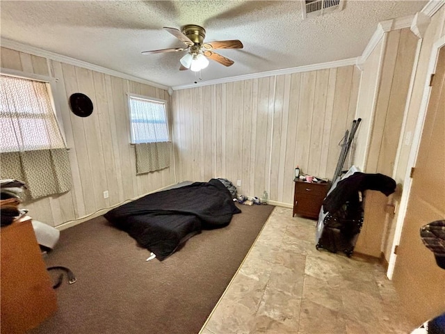 bedroom featuring ceiling fan, wooden walls, ornamental molding, and a textured ceiling