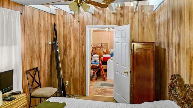 bedroom with light tile patterned floors, ceiling fan, and wooden walls