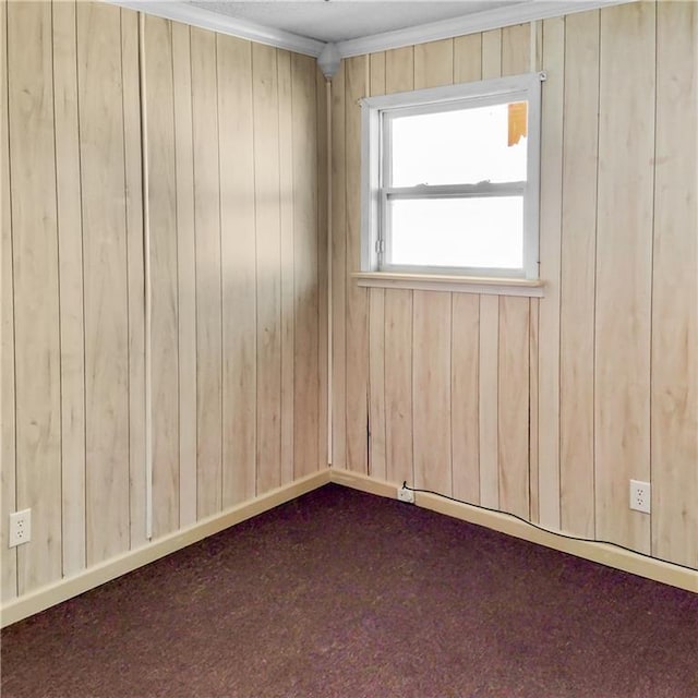 unfurnished room with wooden walls, dark carpet, and crown molding